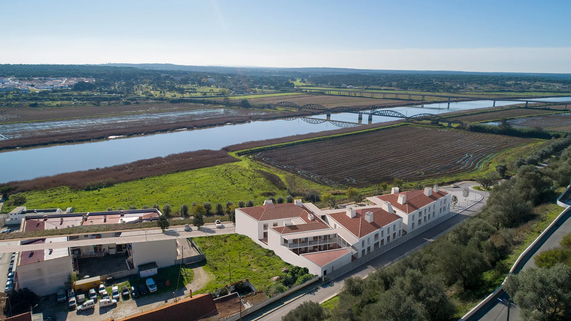 View of the green lands next to the river with a bridge connecting the two banks
